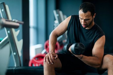 Portrait Of Motivated Black Sportsman Lifting Heavy Dumbbell With One Hand, Handsome Young African American Male Athlete Working Out Biceps At Gym, Making Bodybuilding Workout, Closeup