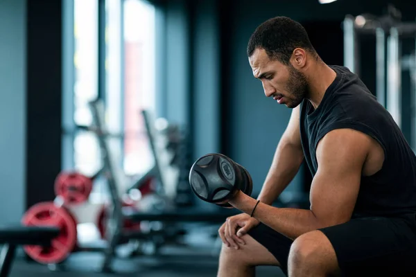 Sport Training. Muscular African American Guy Working Out With Dumbbell At Gym, Athletic Young Black Male Using Sport Equipment For Bodybuilding Workout At Modern Fitness Studio, Copy Space