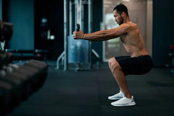 Motivated Athletic Black Man Exercising With Kettlebell At Modern Gym Interior, Side View Shot Of Shirtless Muscular African American Guy Training With Sport Equipment At Fitness Club, Copy Space