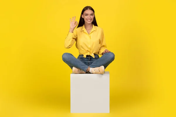 Happy Millennial Lady Gesturing Okay Sitting Cube Green Studio Background —  Fotos de Stock