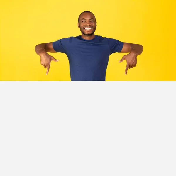 Cheerful Black Male Pointing Fingers Blank Paper Poster Advertising Great — стоковое фото