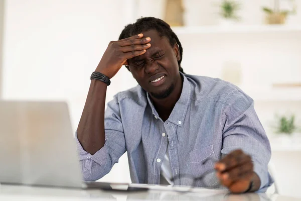 Upset Black Male Suffering Headache While Working Laptop Home Office —  Fotos de Stock