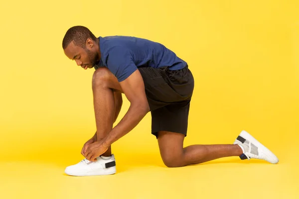 Black Male Runner Lacing Shoes Preparing Race Posing Yellow Studio — Stockfoto