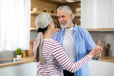 Aged Love. Portrait Of Romantic Elderly Spouses Dancing In Kitchen Interior, Loving Senior Husband And Wife Holding Hands And Looking At Each Other, Enjoying Time At Home Together, Closeup Shot
