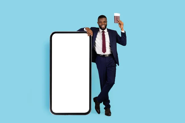 Smiling Black Businessman Pasport Tickets Leaning Huge Blank Smartphone Blue — Foto de Stock