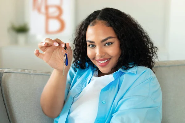 Real Estate Purchase. Happy Black Woman Showing New House Key Smiling To Camera Posing Sitting On Couch At Home. Property Ownership And Rental Service Concept