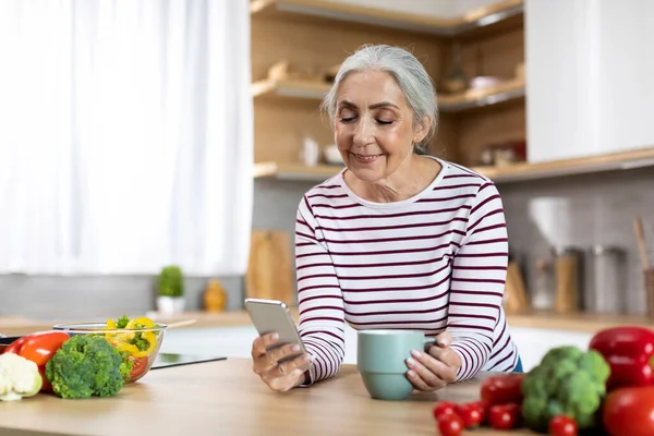 Portrait Smiling Senior Woman Using Smartphone Drinking Coffee Kitchen Happy — Stockfoto