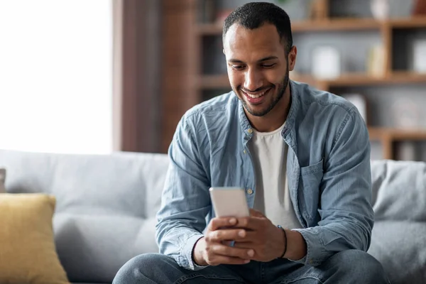Handsome Young Black Man Using Smartphone While Relaxing Couch Home — Stockfoto