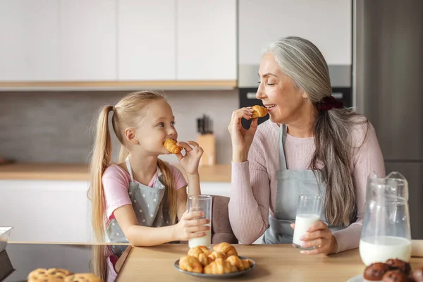 Cheerful Caucasian Aged Grandmother Small Granddaughter Aprons Glasses Milk Eat — Fotografia de Stock