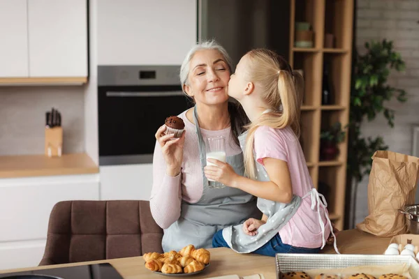 Cheerful European Little Granddaughter Kisses Her Grandmother Cheek Enjoy Cookies — Stock Fotó