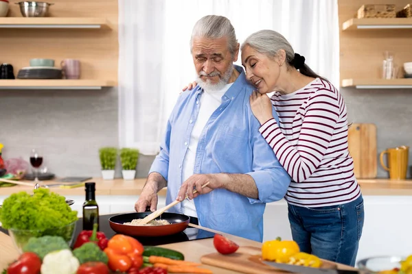 Portrait Of Loving Senior Couple Making Meal Together In Kitchen, Happy Elderly Man And Woman Cooking Healthy Lunch At Home, Romantic Aged Spouses Bonding While Preparing Tasty Food, Copy Space