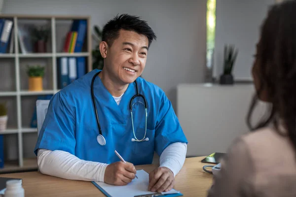 Весела Дружня Зріла Корейська Людина Лікар Консультує Молодого Афроамериканського Пацієнта — стокове фото