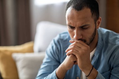 Closeup Portrait Of Thoughtful Young Black Man At Home Interior, Depressed Pensive African American Guy Resting Chin On Hands And Looking Away, Suffering Mental Breakdown Or Seasonal Depression