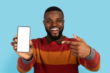 Online Offer. Excited Black Man Pointing At Big Blank Smartphone In His Hand, Cheerful African American Guy Demonstrating Phone With White Screen At Camera, Recommending New App, Collage, Mockup