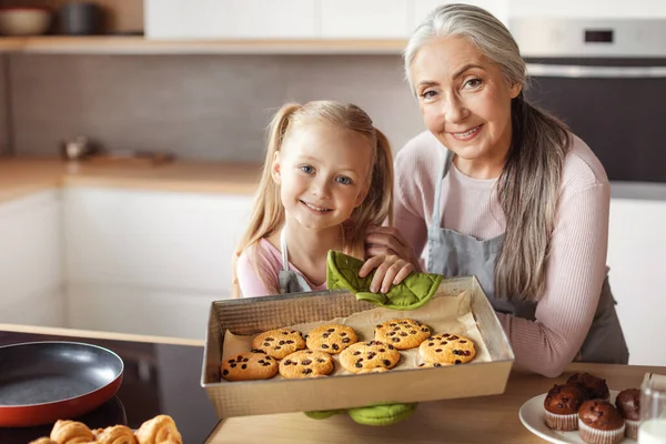Smiling Little Girl Senior Female Aprons Show Homemade Fresh Cookies — Φωτογραφία Αρχείου