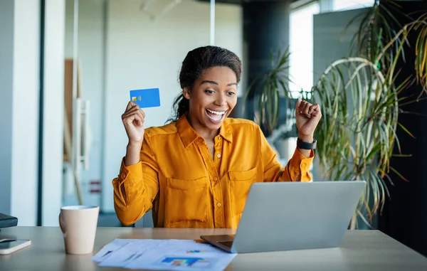 Overjoyed Black Female Office Worker Holding Credit Card Front Laptop — Zdjęcie stockowe