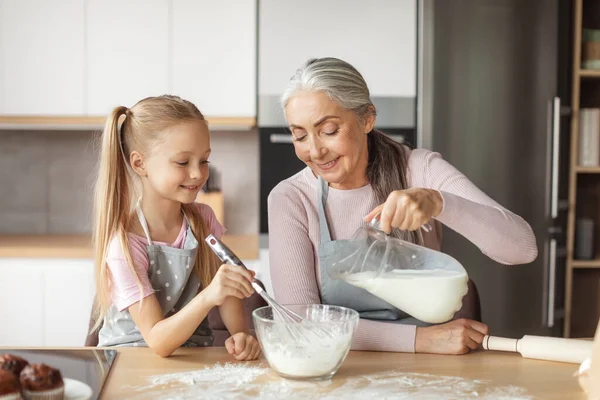 Happy European Elderly Grandmother Little Granddaughter Aprons Pour Milk Dough — Stockfoto
