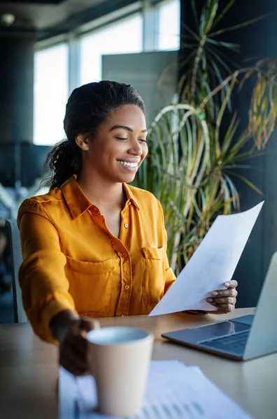 Happy Black Female Office Manager Holding Coffee Cup Reading Documents — Stok fotoğraf