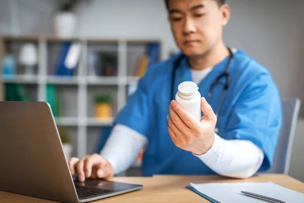 Serious Adult Chinese Male Doctor Laptop Looks Jar Pills Clinic — Stockfoto