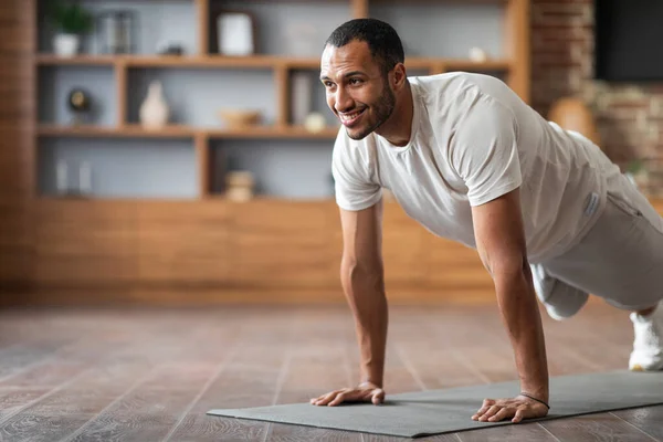 Active Sporty Black Male Training At Home, Making Plank Exercise, Handsome Athletic African American Man Enjoying Domestic Workout, Smiling Guy Exercising In Living Room Interior, Copy Space