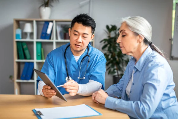 Serious Middle Aged Asian Man Doctor Showing Tablet Retired European — Stockfoto