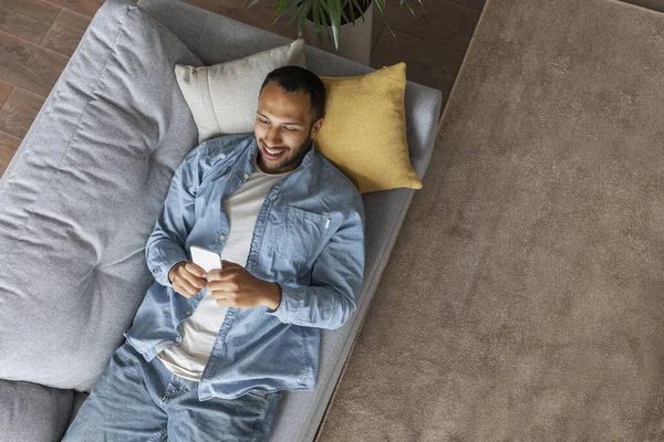 Black Happy Man Smartphone Relaxing Comfortable Couch Home Top View — Foto de Stock