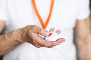 Unrecognizable senior man pushing panic button on emergency equipment for elderly people, closeup photo. Elderly man pressing alarm button for emergency hung on his chest, cropped