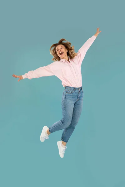 Vertical Shot Joyful Woman Posing Mid Air Having Fun Blue — стоковое фото