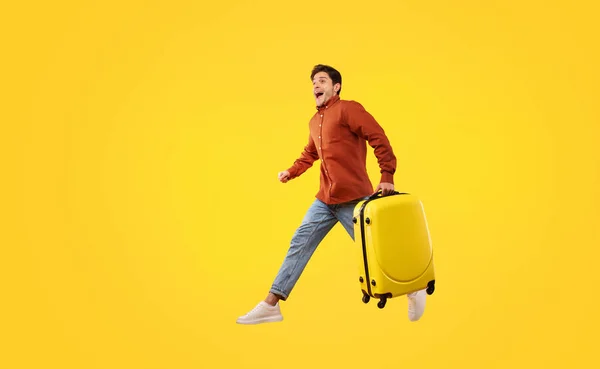 Vacation Concept Excited Male Tourist Suitcase Running Jumping Mid Air — Zdjęcie stockowe