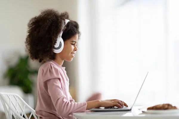 Happy Black Preteen Girl Sitting Desk Home Using Modern Laptop — ストック写真