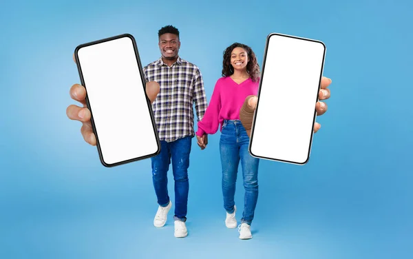 Cheerful Black Couple Demonstrating Blank Smartphones While Walking Blue Studio — Φωτογραφία Αρχείου