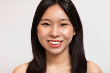 Natural beauty. Portrait of happy korean lady with natural makeup and healthy smooth skin smiling at camera, posing on white studio background