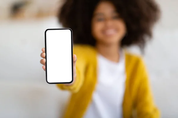 African american child holding brand new smartphone with white blank screen, showing newest entertaining mobile application for kids, mockup, copy space, blurred background