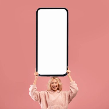 Joyful Young Blonde Woman Holding Big Blank Smartphone Above Head, Smiling Millennial Female Demonstrating Mobile Phone With White Screen While Standing Isolated On Pink Background, Collage, Mockup