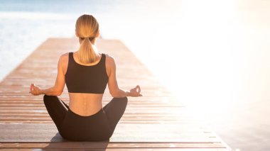 Life Harmony Concept. Rear View Of Slim Female Meditating Outdoors Near The Sea, Unrecognizable Relaxed Woman Sitting On Wooden Pier In Lotus Position, Practicing Morning Yoga Outside, Copy Space