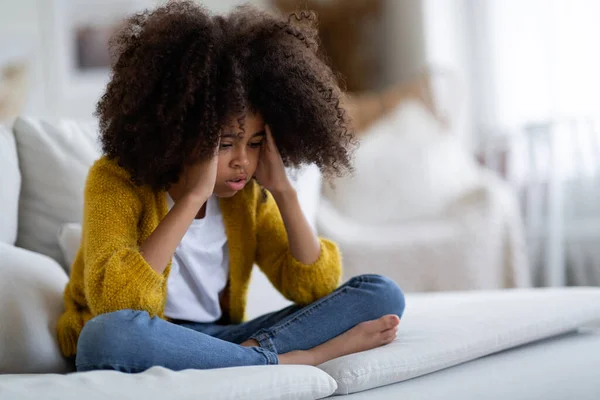 Overwhelmed Black Little Girl Bushy Hair Sitting Couch Home Touching — стоковое фото