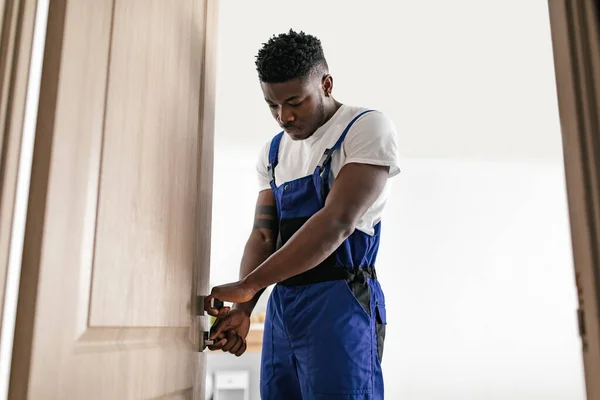 African American Repairman Fixing Door Standing Indoor Wearing Blue Coverall — Stockfoto