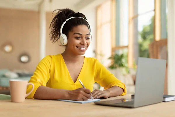 Smiling Black Lady Wireless Headphones Working Laptop Taking Notes Paper — ストック写真