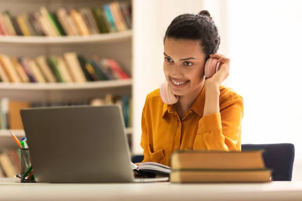 Happy Mixed Race Lady Touching Wireless Headphones Looking Laptop Screen — Fotografia de Stock