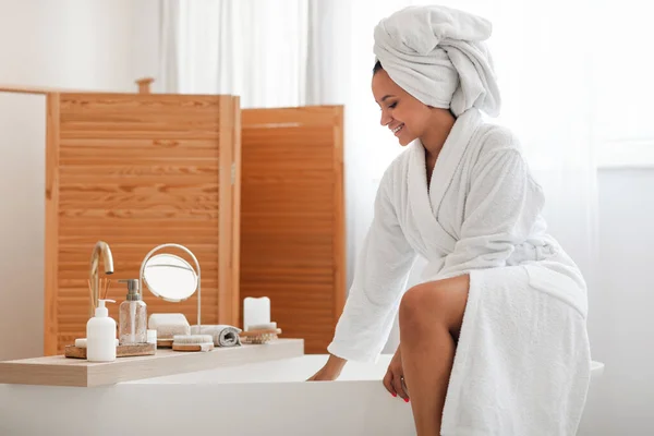 Happy Lady Wearing Bathrobe Sitting Bathtub Touching Water Preparing Bath — 스톡 사진