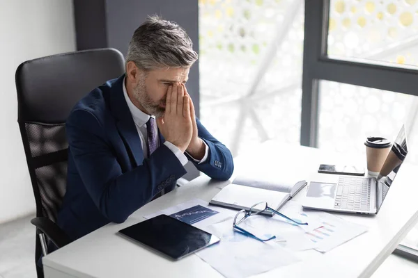 Business Failure. Portrait Of Depressed Middle Aged Businessman Sitting At Desk In Office, Upset Male Entrepreneur In Suit Covering Face With Hands, Suffering Problems At Work, Copy Space