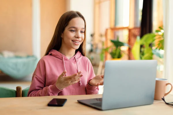 Positive Teen Girl Video Calling Laptop Gesturing Webcamera Sitting Desk — стоковое фото