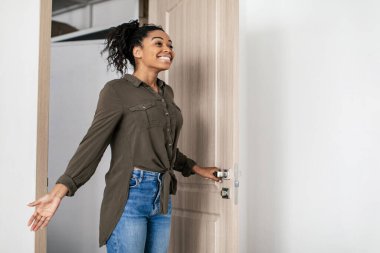 Joyful Black Female Opening Entry Door Entering New Rented Apartment After Relocation, Looking Aside. Real Estate Purchase And Rent Concept. Side View Shot