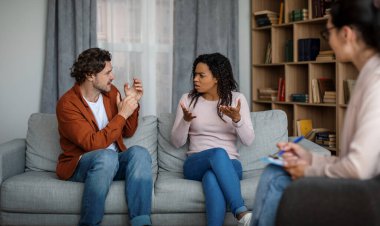 Offended young international family quarreling at meeting with psychologist in office clinic interior. Family psychological therapy, consultation with doctor, relationships of people and emotions