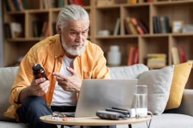 Elderly man seating on sofa, making distant video call, senior patient looking at laptop screen, communicating with doctor therapist online, asking how to take medicine, copy space. Telemedicine