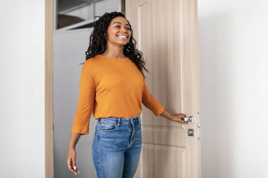 Cheerful Black Lady Entering Home Opening Door Indoors. Real Estate Female Buyer Coming Into Room In Her New Rented Apartment. Property Purchase And Ownership Concept