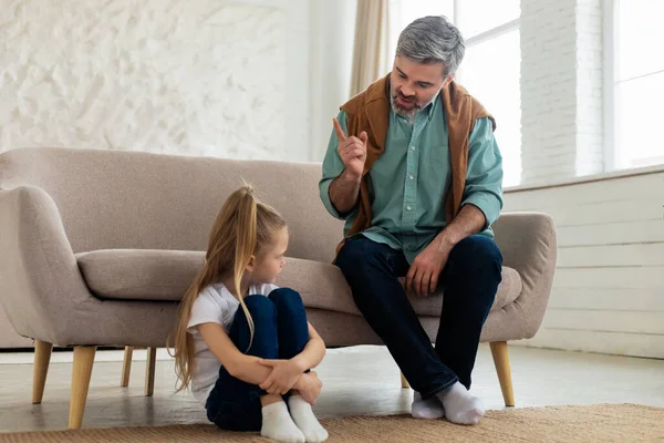Strict Father Scolding Sad Kid Daughter For Bad Behavior Sitting At Home. Dad Explaining Something To His Child Having Issues In Relationship. Family Conflicts And Unhappy Childhood
