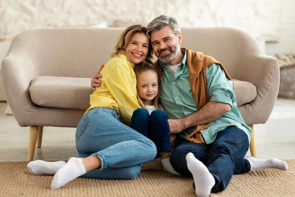 Happy Parents Kid Daughter Hugging Sitting Floor Smiling Camera Posing — Stockfoto