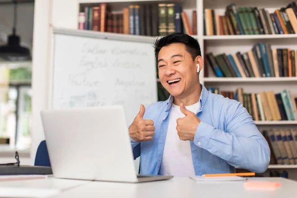 Teaching Joyful Asian Male Tutor Gesturing Thumbs Laptop Computer Approving — Zdjęcie stockowe