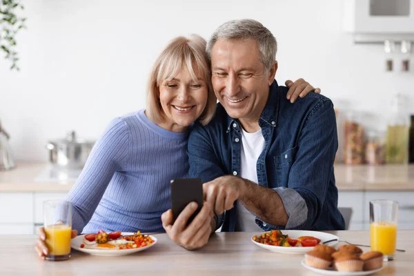 Positive Elderly Husband Wife Using Cell Phone While Having Breakfast — Stok fotoğraf
